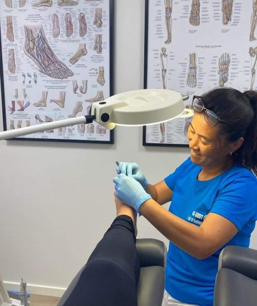 En kvindelig fodterapeut behandler fødder i Aalborg Fodterapi klinik